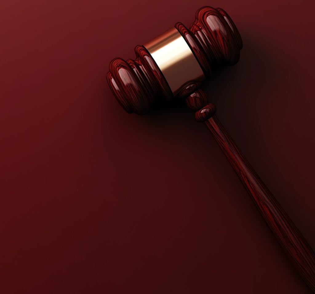 A wooden gavel on a red background. - Immo Safe